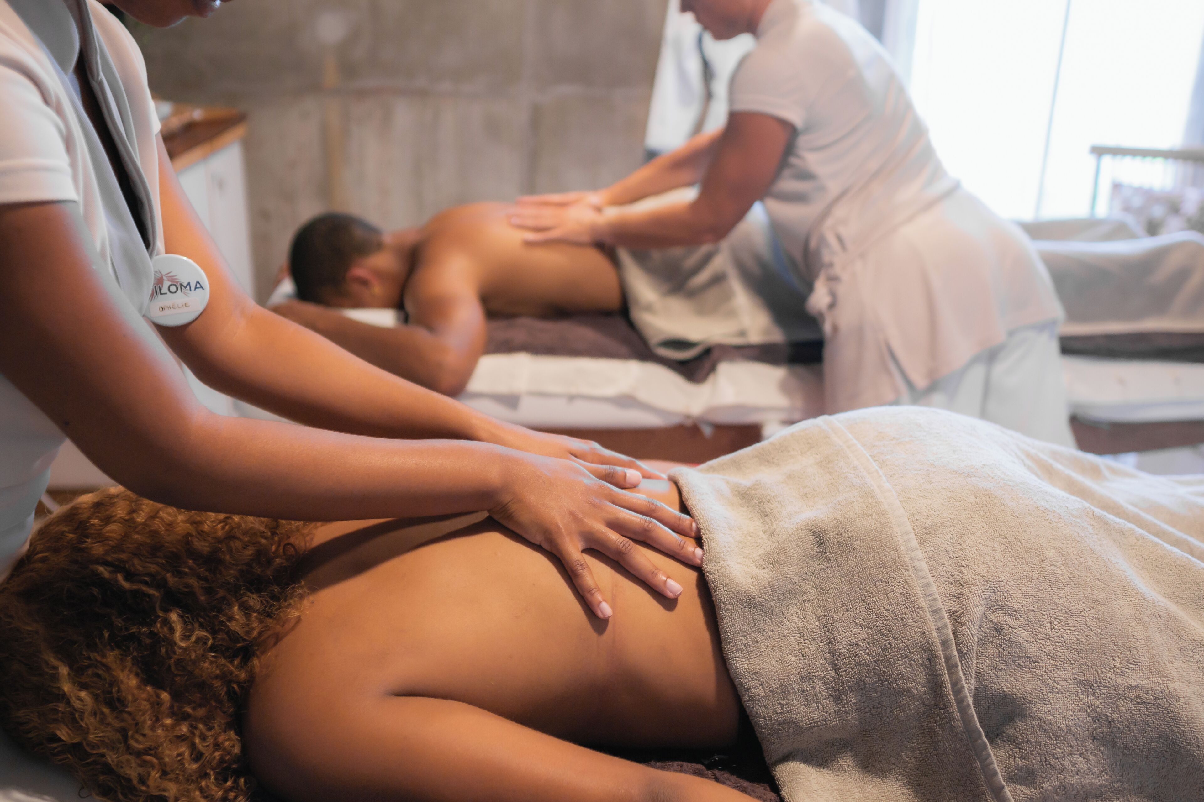 A massage therapy session in a spa setting with a client lying face down on a massage table, receiving attention from a therapist.