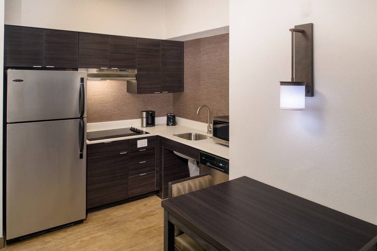 Una cocina moderna con gabinetes de madera oscura, electrodomésticos de acero inoxidable y lavavajillas integrado.