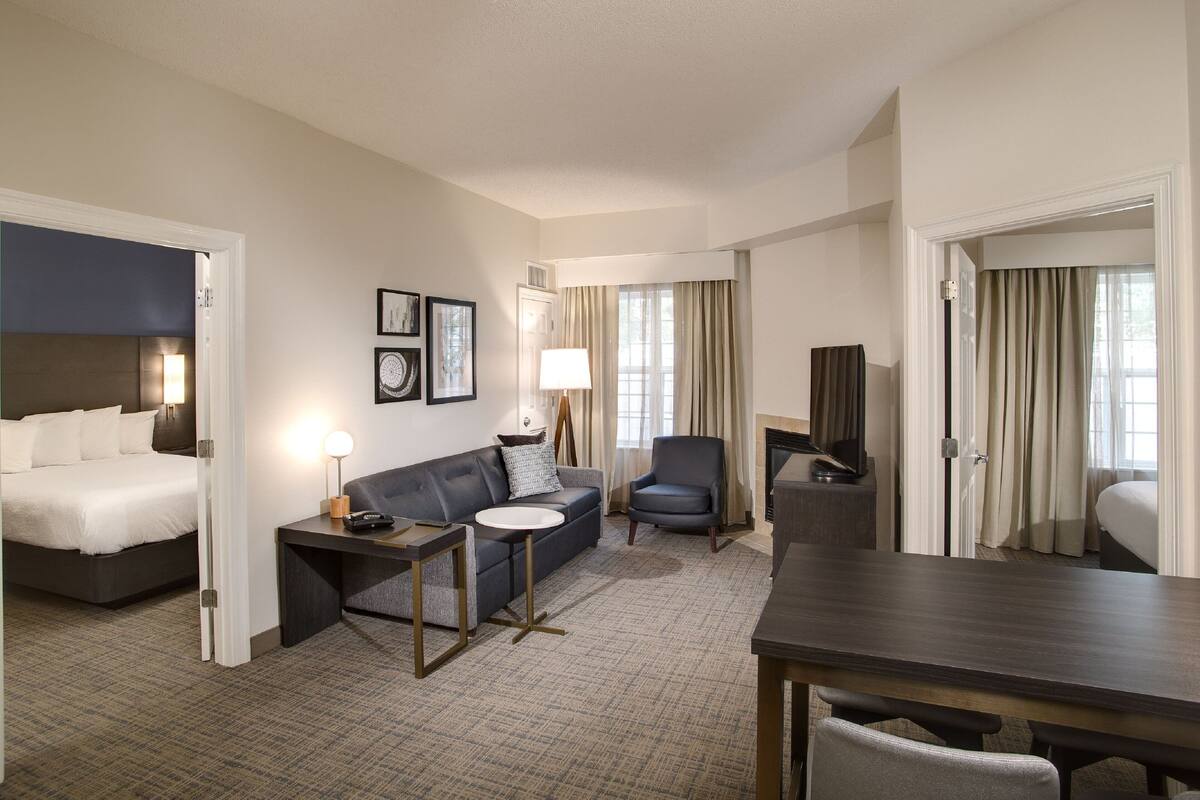 Una habitación de hotel con cama, sofá, escritorio, silla y televisor.