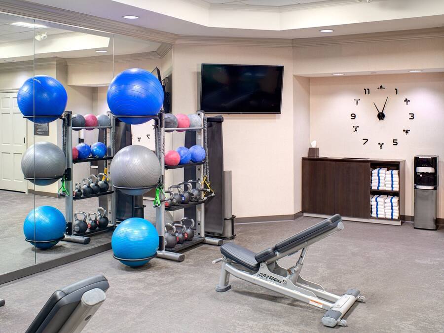 A gym with exercise equipment, a TV, and a clock on the wall.