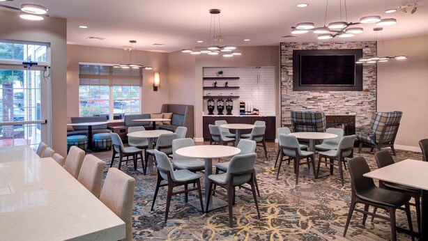 A hotel lobby with multiple seating areas, a bar, and a large TV screen. - Residence Inn by Marriott Columbia Northeast/Fort Jackson Area (Columbia)