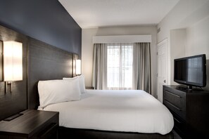 Ein Hotelzimmer mit einem großen Bett, einem Flachbildfernseher, einem Nachttisch und einem Fenster mit Vorhängen.