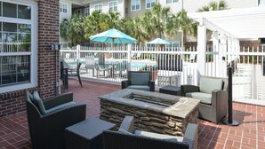 An outdoor patio area with wicker furniture, a stone fire pit, and umbrellas. - Residence Inn by Marriott Columbia Northeast/Fort Jackson Area (Columbia)