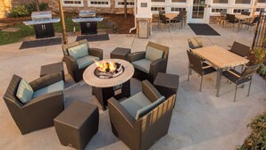 An outdoor patio with wicker furniture, a fire pit, and a grill area. - Residence Inn by Marriott Wichita East at Plazzio (Wichita)