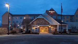 A hotel with a stone facade, a prominent entrance, and a flagpole with an American flag. - Residence Inn by Marriott Wichita East at Plazzio (Wichita)