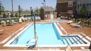 A rectangular swimming pool with a depth marker, surrounded by lounge chairs and a small stone building. - Residence Inn by Marriott Wichita East at Plazzio (Wichita)