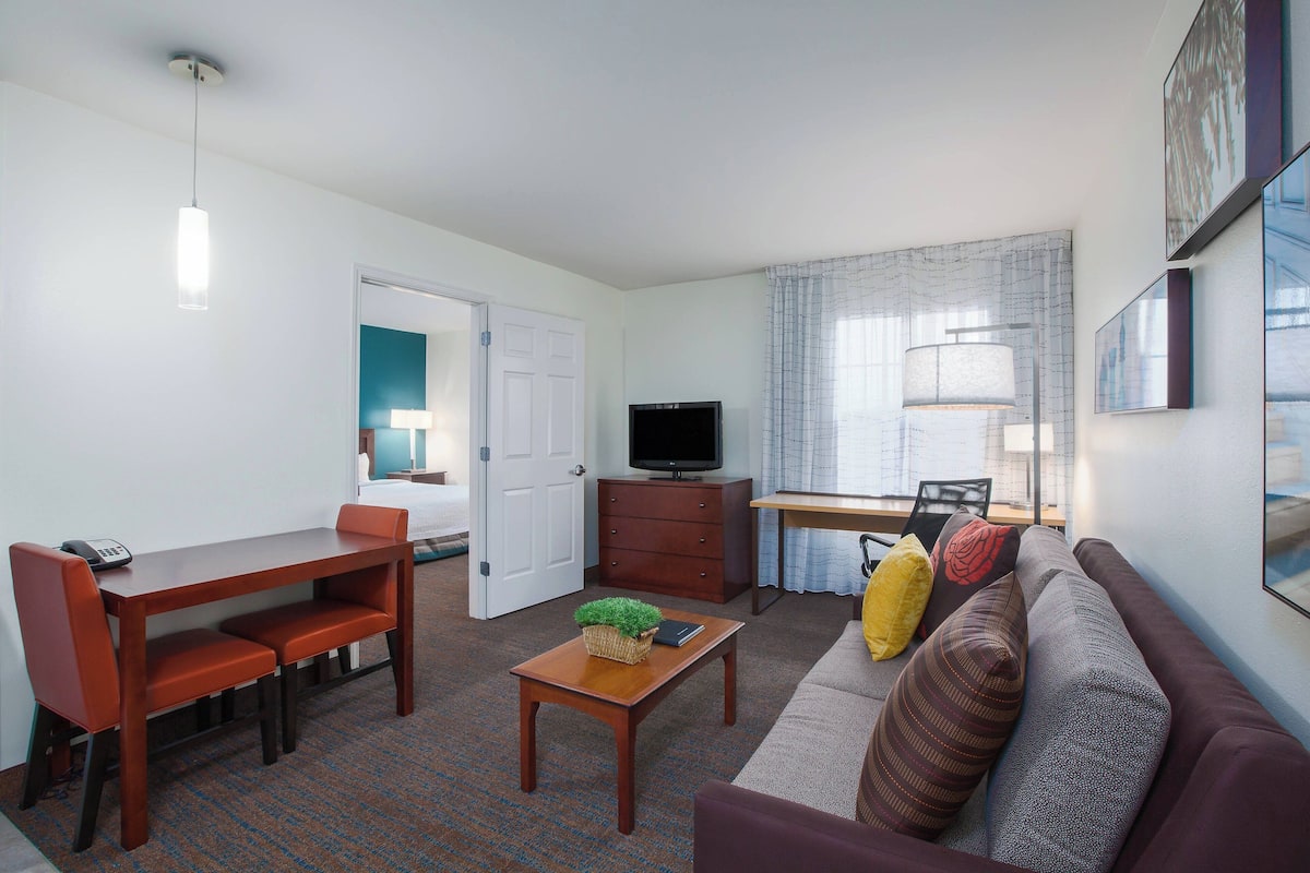 A compact living space with a dining table, sofa, and a television.