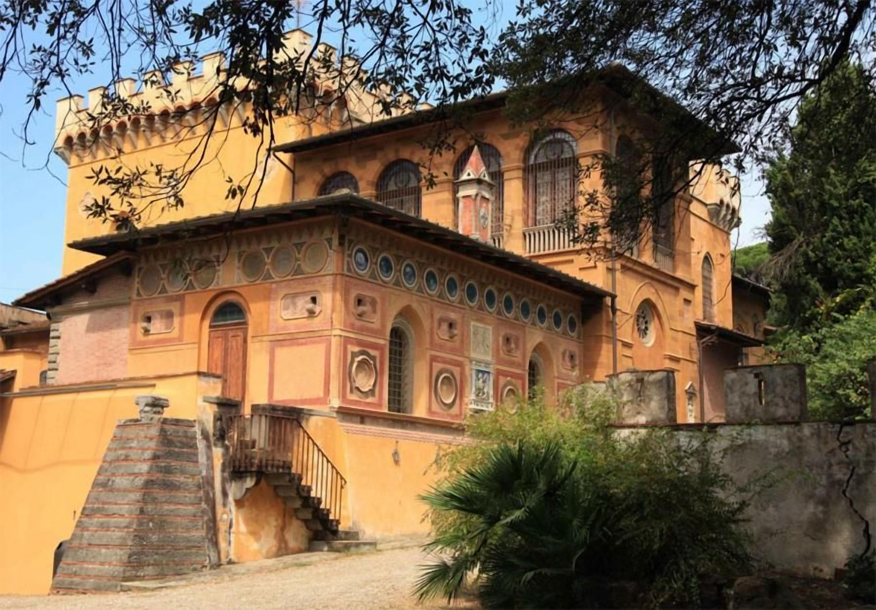 A historic building with a central courtyard, a staircase leading to the entrance, and a small garden area.