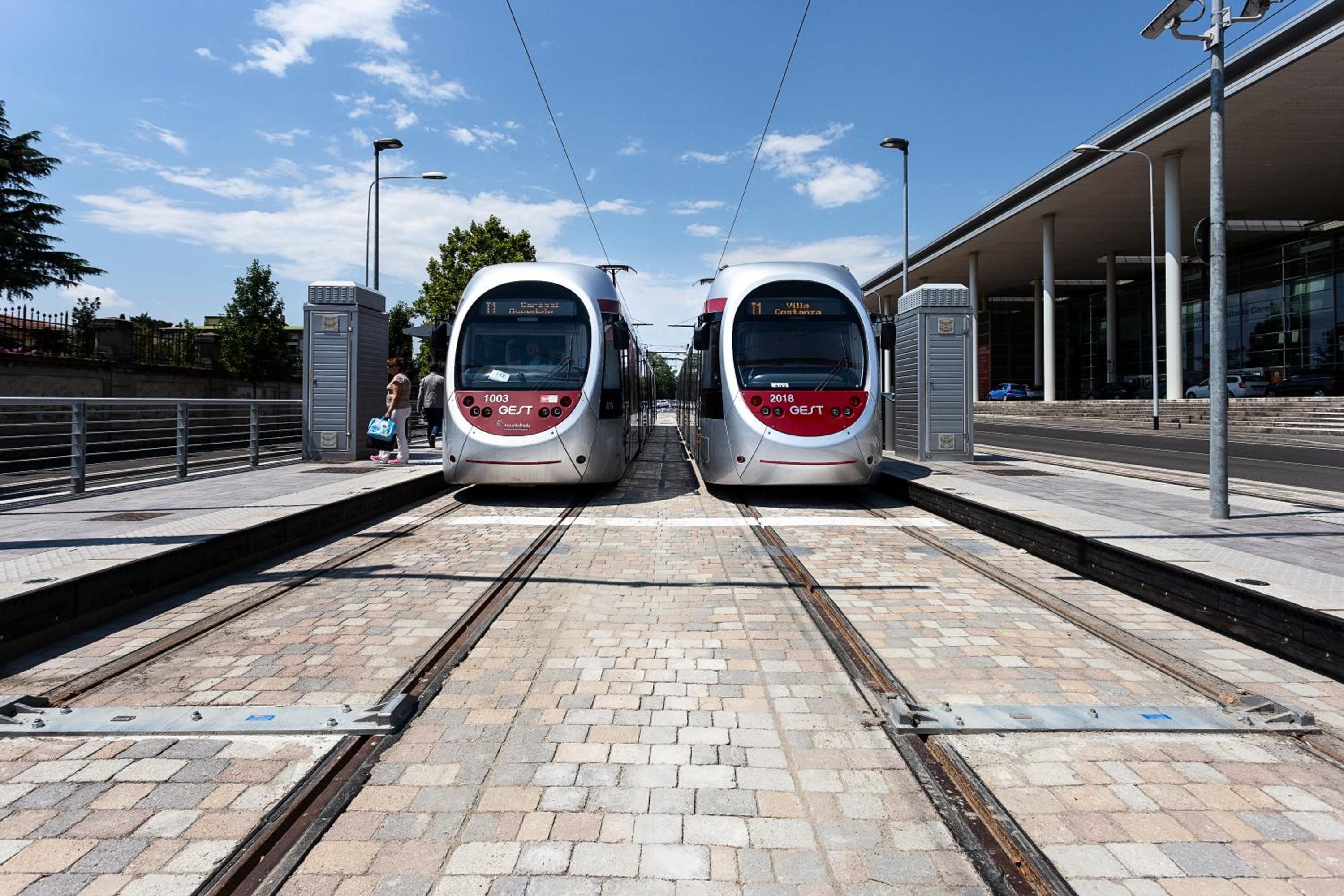 Deux trains modernes sur le quai d’une gare, avec un ciel dégagé.