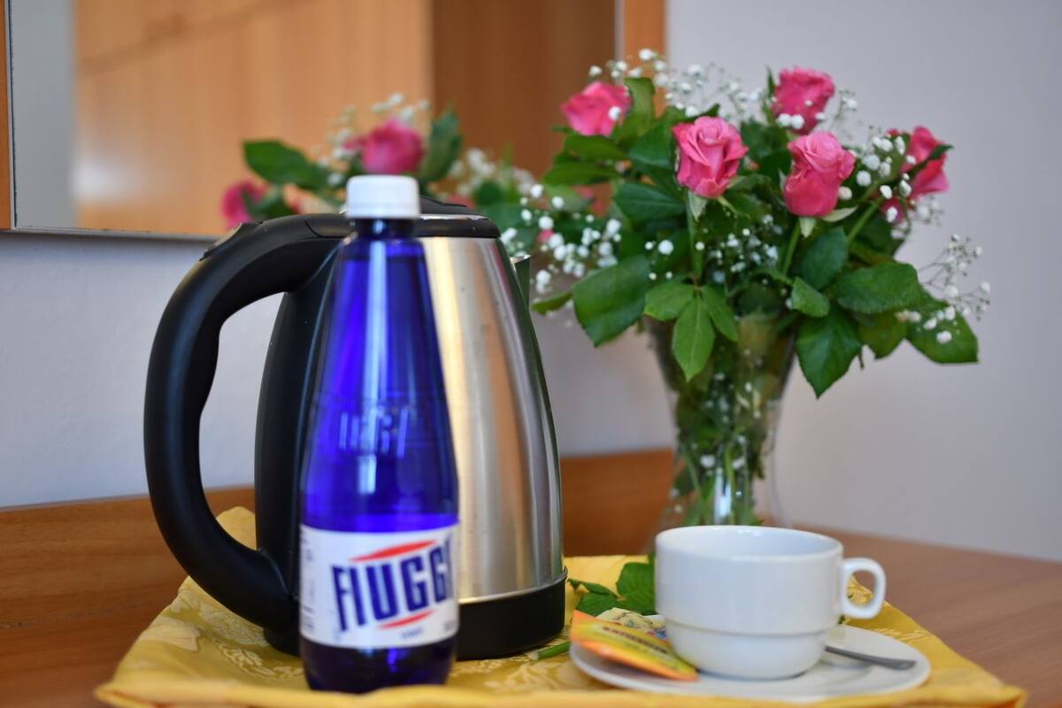 A coffee maker, a mug, and a bouquet of flowers on a table.