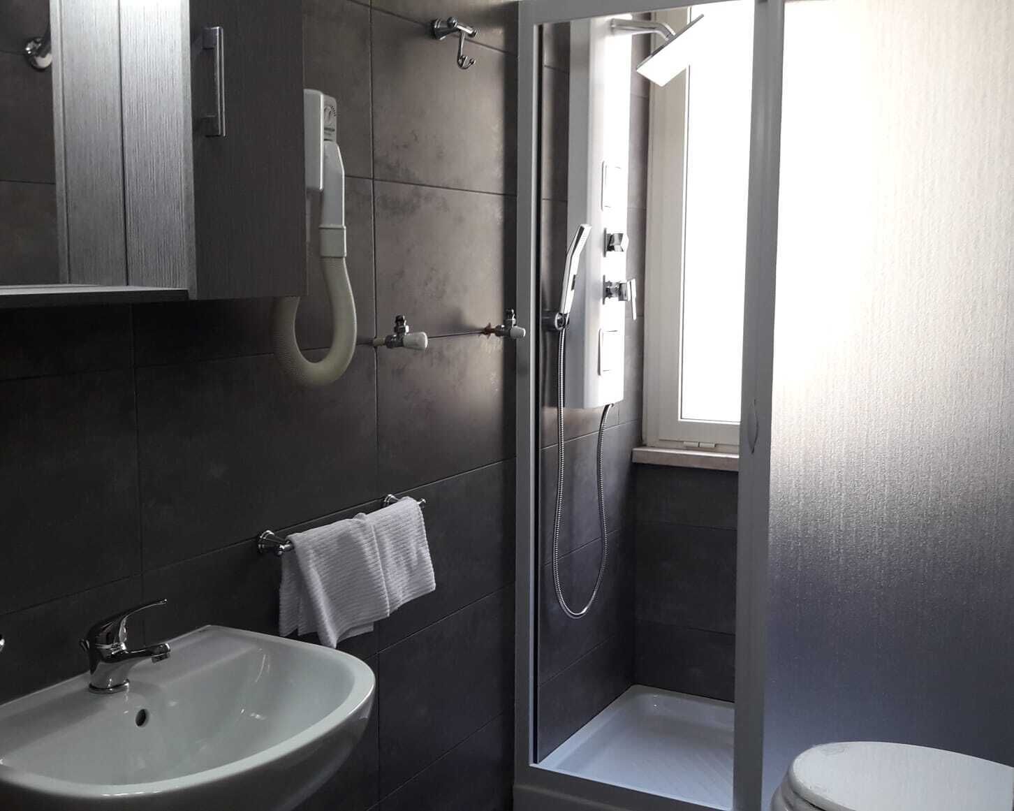 Une salle de bain moderne avec un lavabo blanc, une douche et des toilettes.