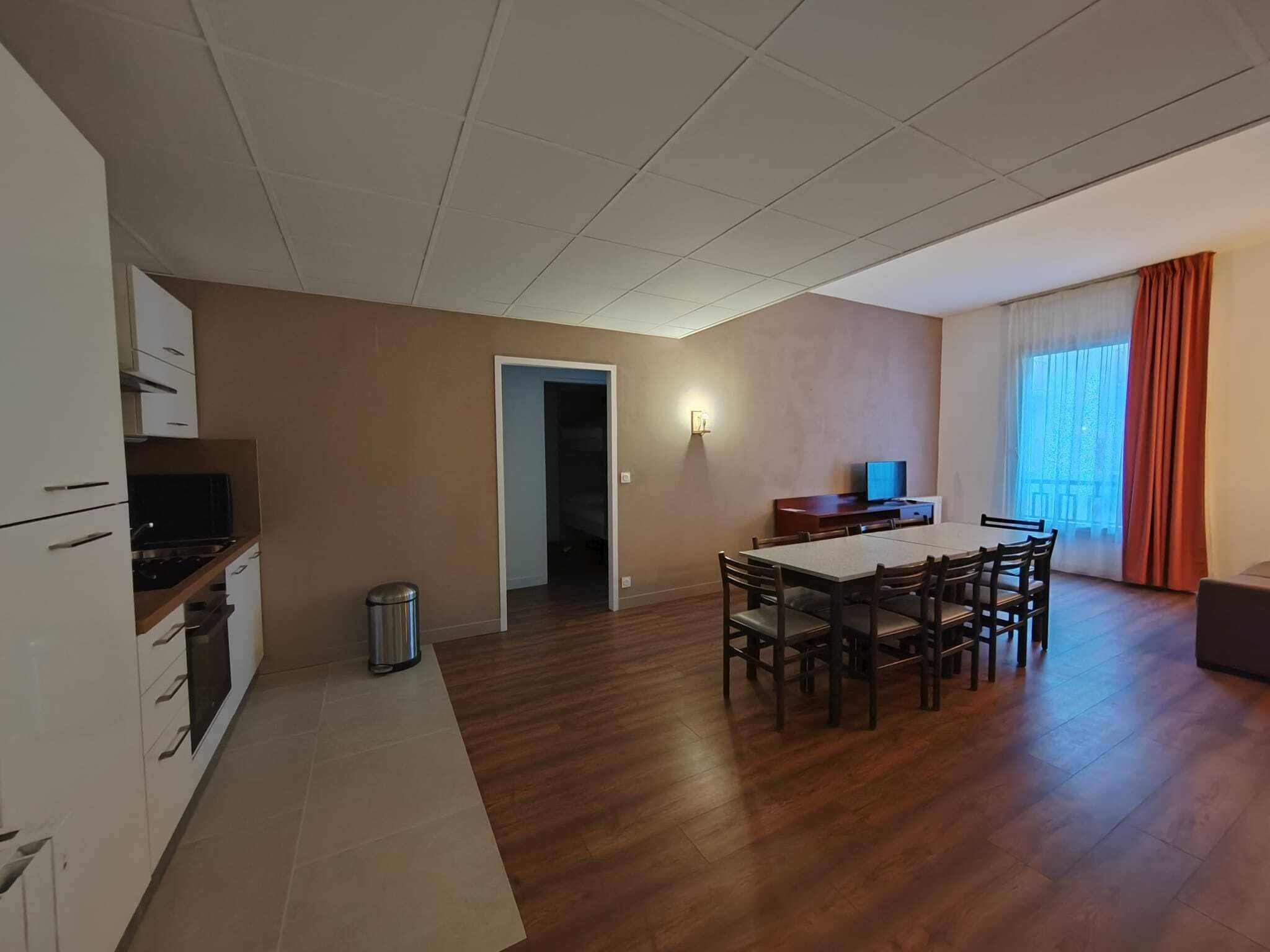 Un espacio habitable amplio con una mesa de comedor y sillas, una kitchenette y un televisor.
