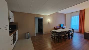 Un espacio habitable amplio con una mesa de comedor y sillas, una kitchenette y un televisor.