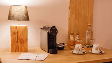 Una mesa de madera con una máquina de café, una lámpara y algunos condimentos.
