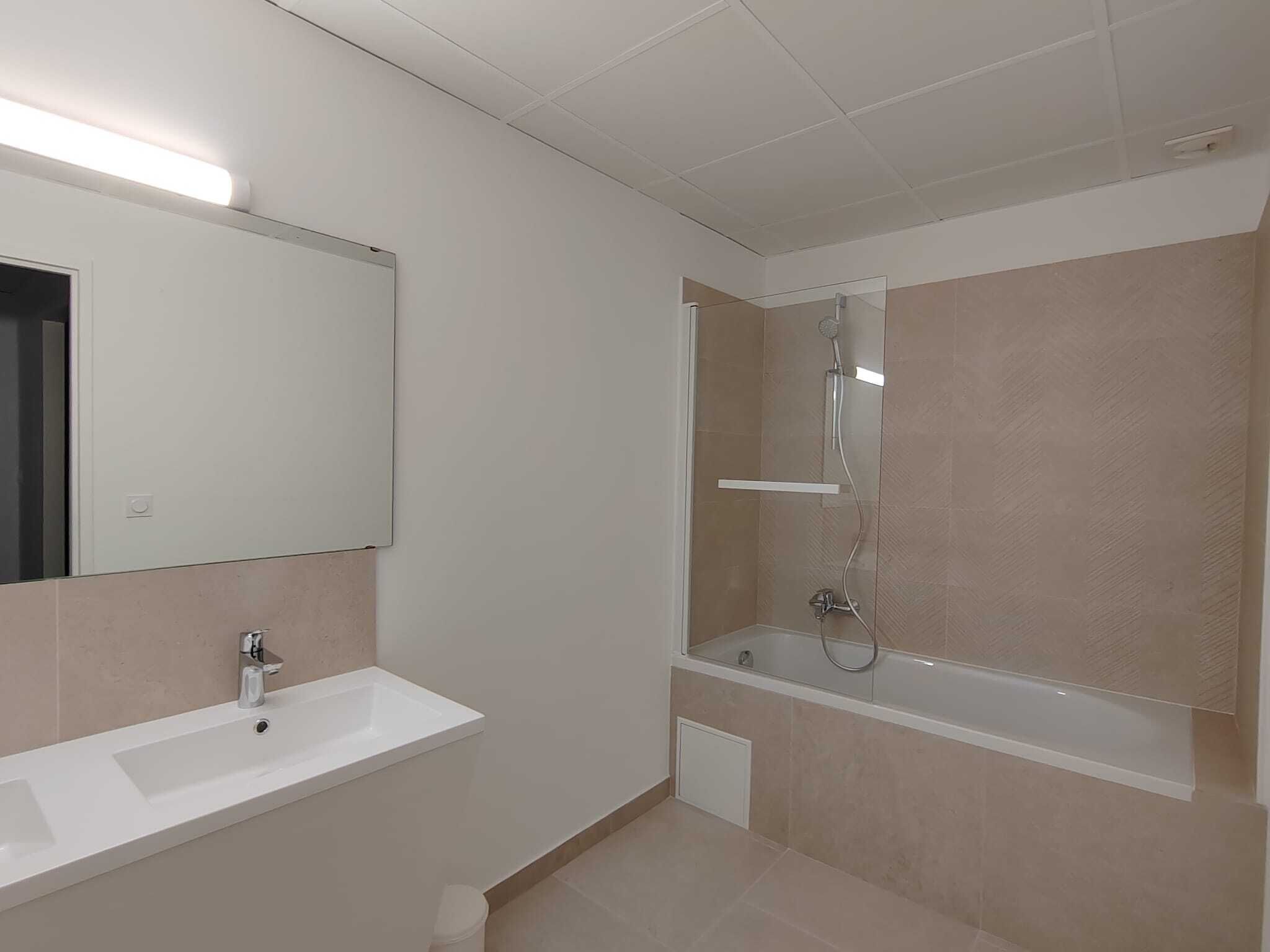 A modern bathroom with a white sink, mirror, and glass-enclosed shower.