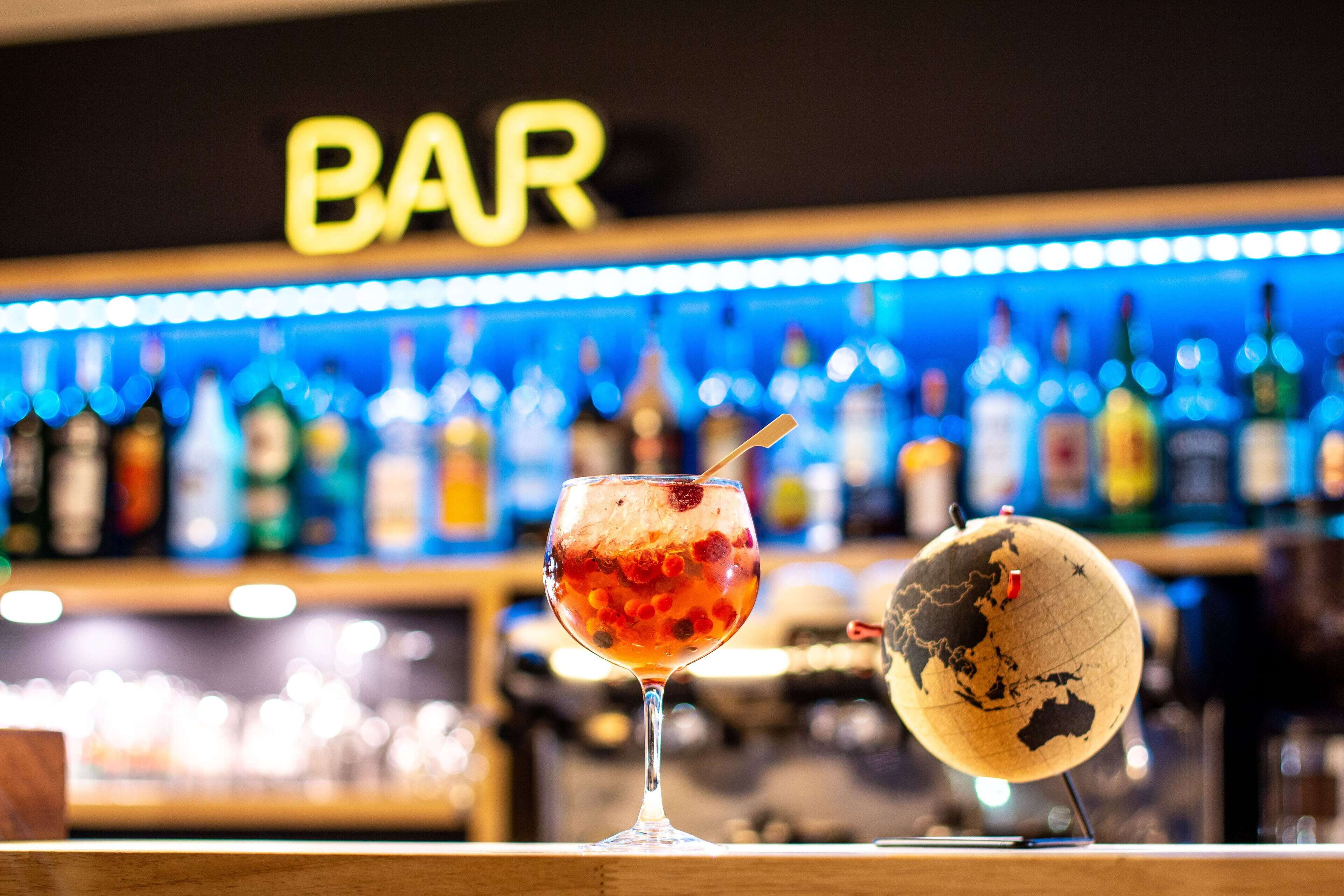 Un bar con una copa de bebida roja y un globo terráqueo sobre la barra.