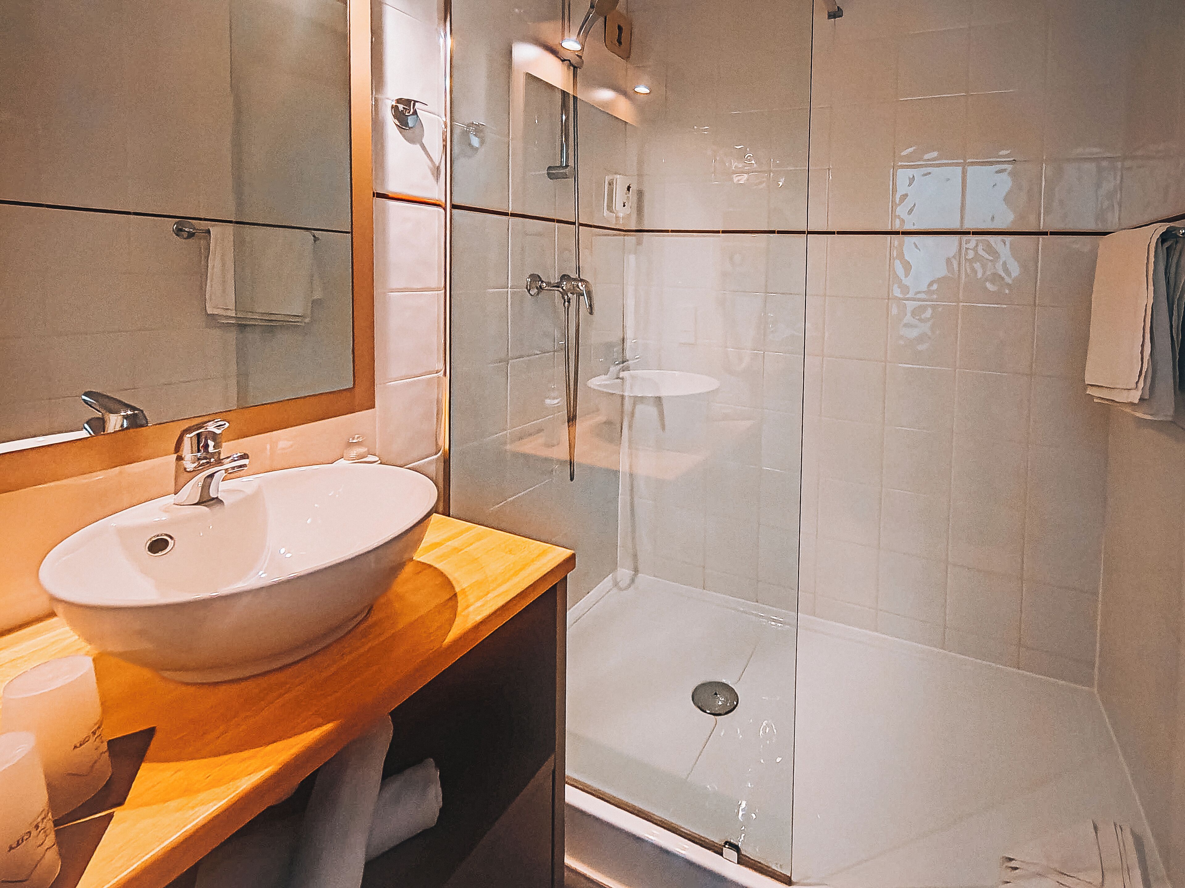 A bathroom with a sink, mirror, and glass-enclosed shower.