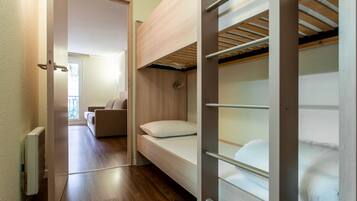 A compact room with a bunk bed, a sofa, and a radiator.