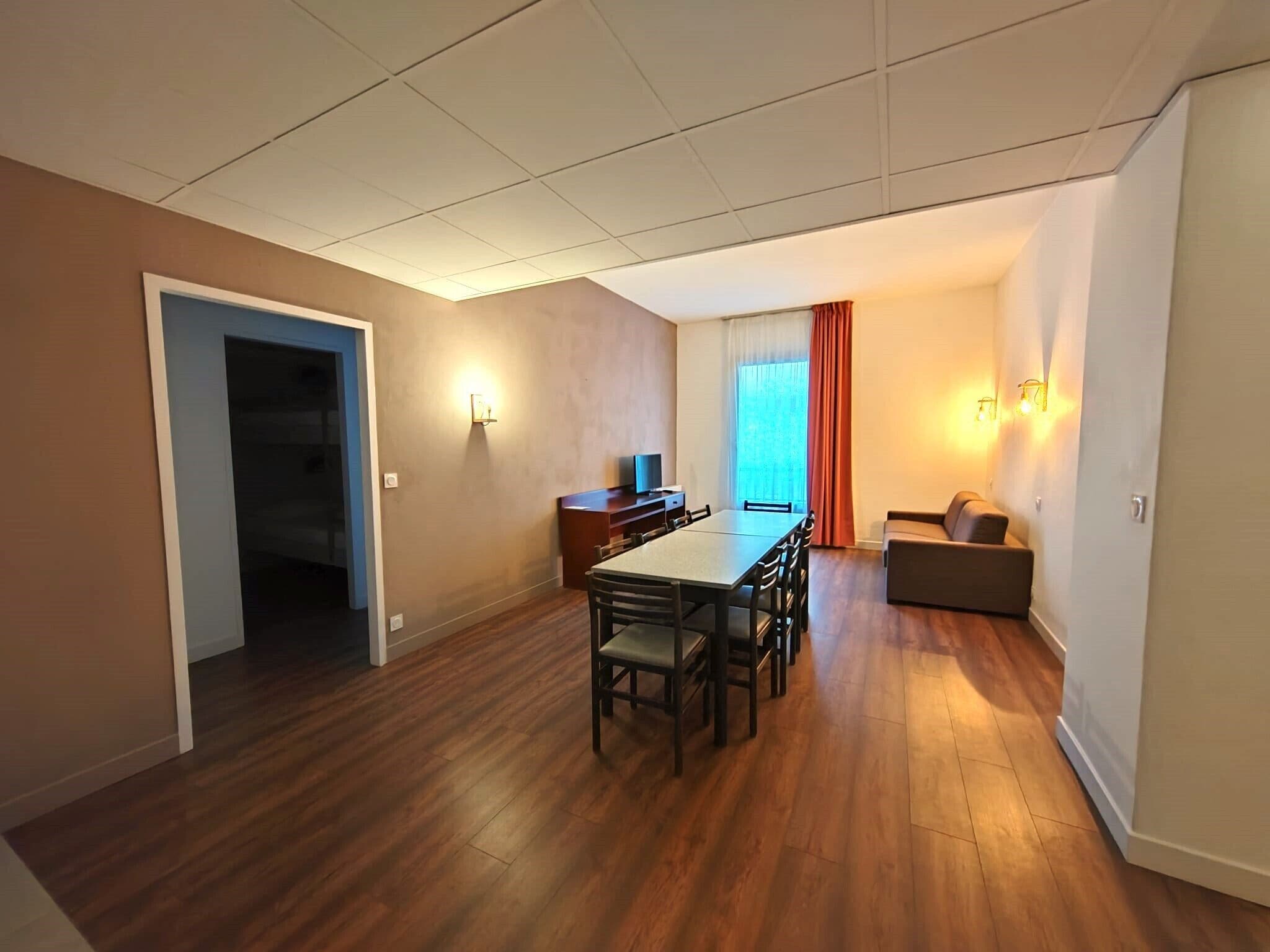 Un soggiorno moderno con zona pranzo, pavimento in legno, un divano e una TV.