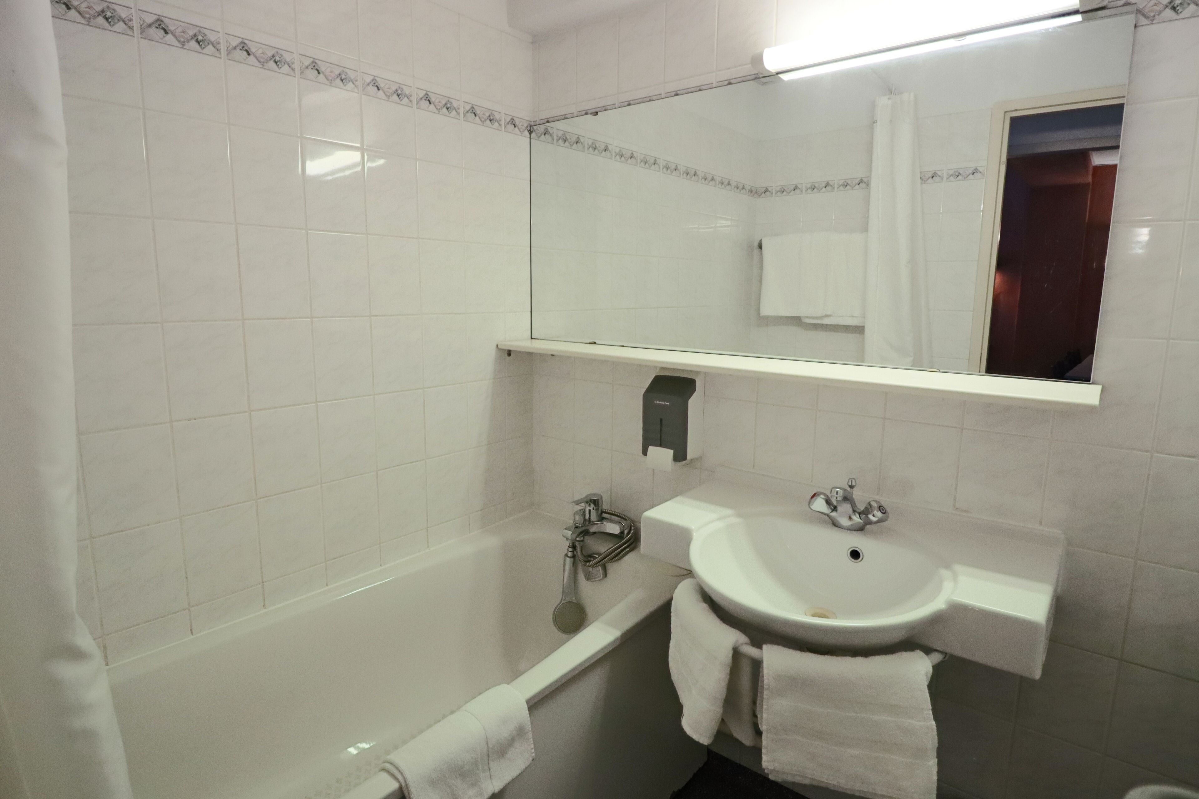 Une salle de bain avec une baignoire, un lavabo et un miroir.