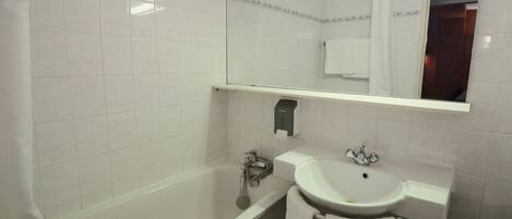 A bathroom with a bathtub, a sink, and a mirror.