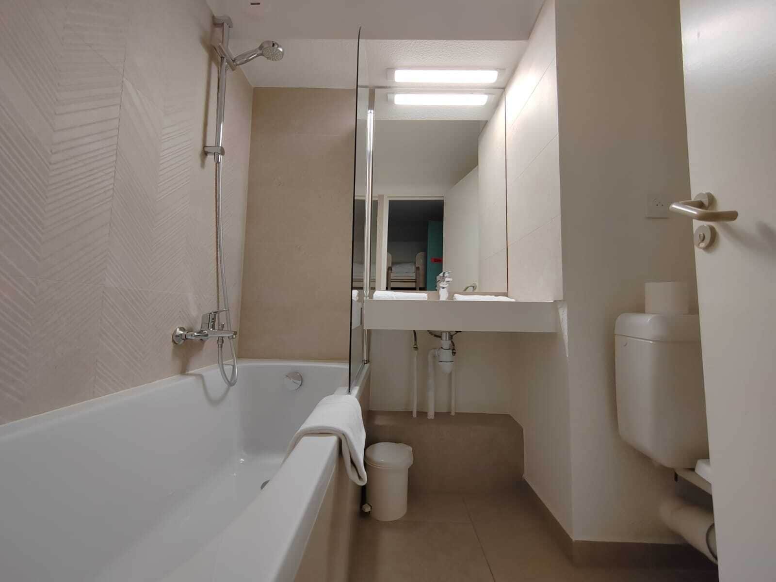 A modern bathroom with a bathtub, a shower, a sink, and a toilet.