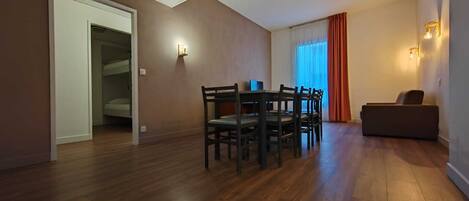 Amplia sala de estar con una mesa y sillas de comedor, un sofá y una ventana con cortinas.