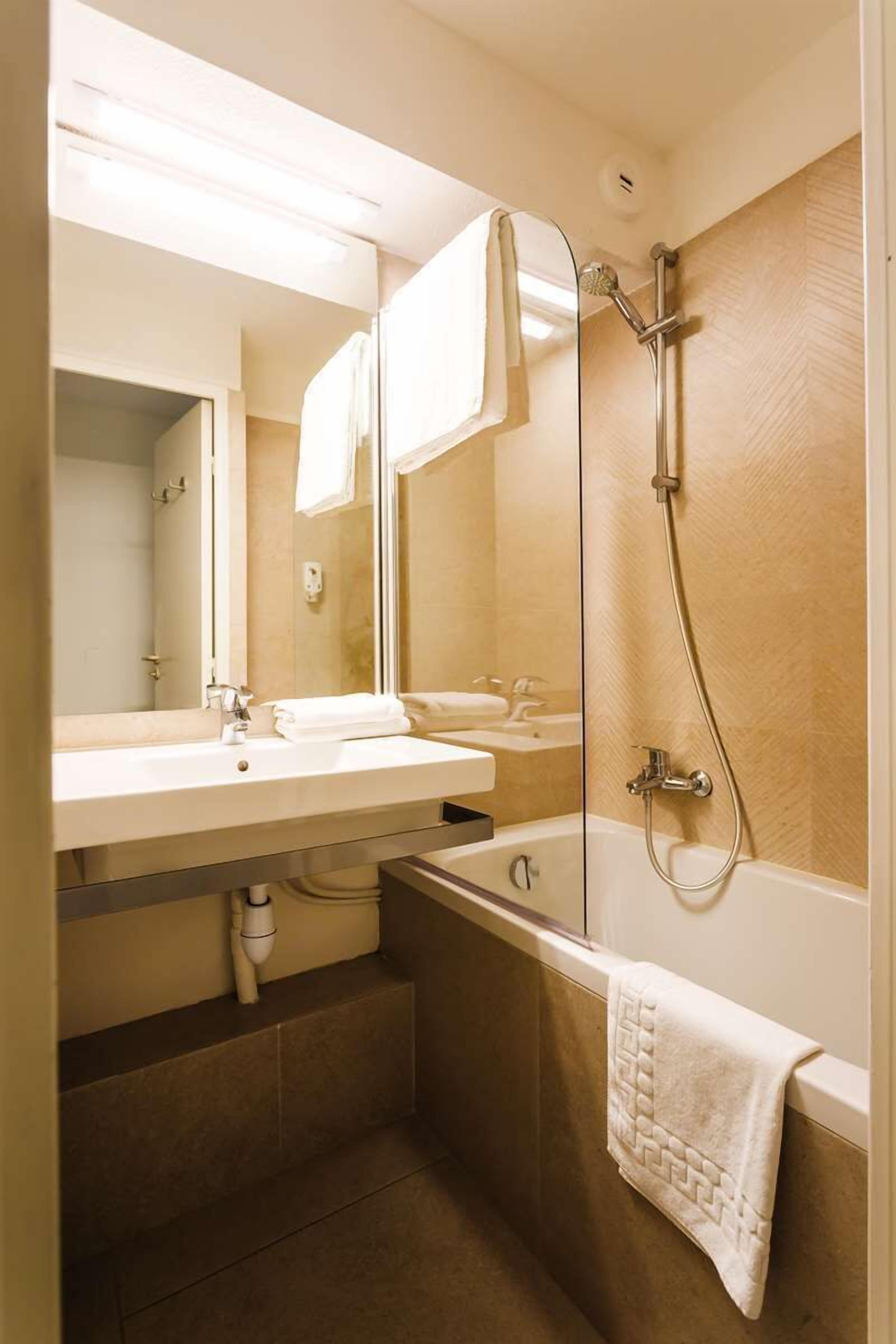 Une salle de bain avec un lavabo, un miroir et une douche.
