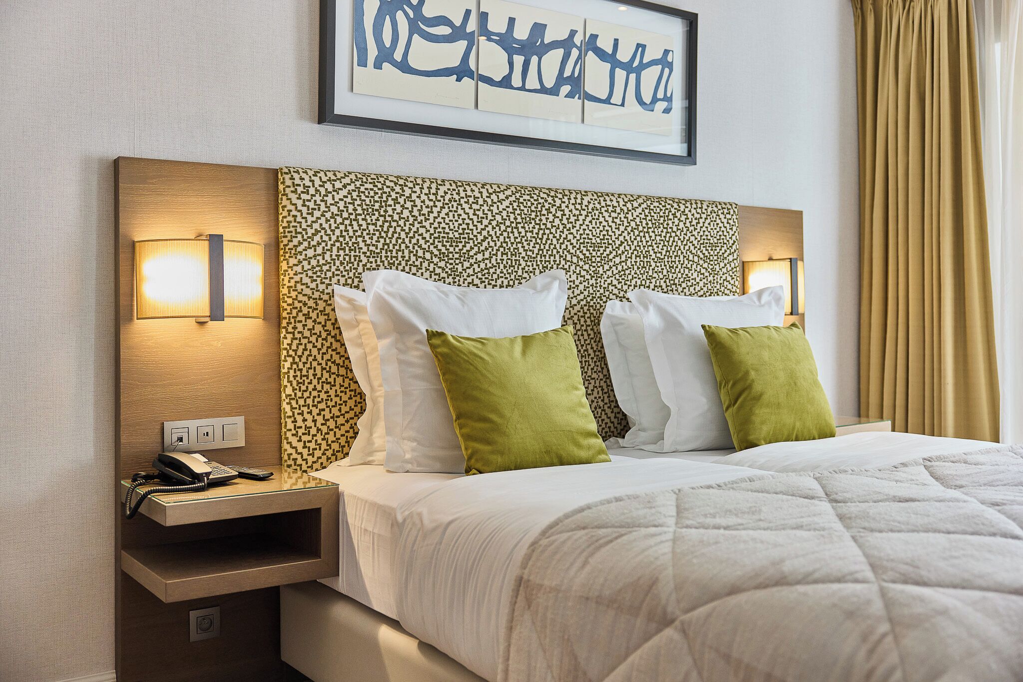 Ein Hotelzimmer mit einem Bett, einem Nachttisch mit Telefon und einer Wandleuchte.