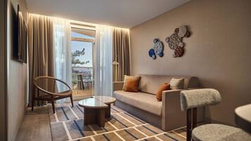 A modern living room with a sofa, armchair, coffee table, and a view through a glass door to an outdoor area.