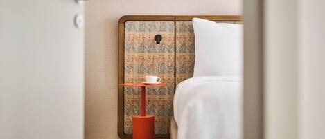 Ein Hotelzimmer mit einem Bett, einem kleinen Tisch mit einer Tasse und einem gemusterten Kopfteil.