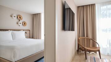 A hotel room with a bed, a chair, a TV, and curtains.