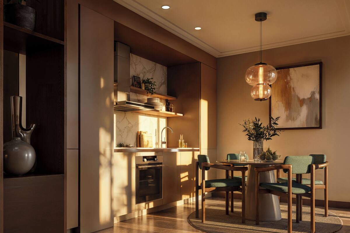 Una cocina moderna con electrodomésticos integrados, un comedor con una mesa redonda y sillas, y una lámpara colgante.