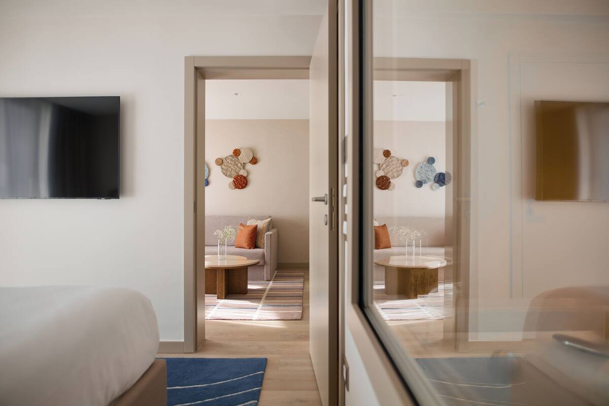 Una habitación de hotel con cama, televisión, sofá y zona de comedor con mesa y sillas.
