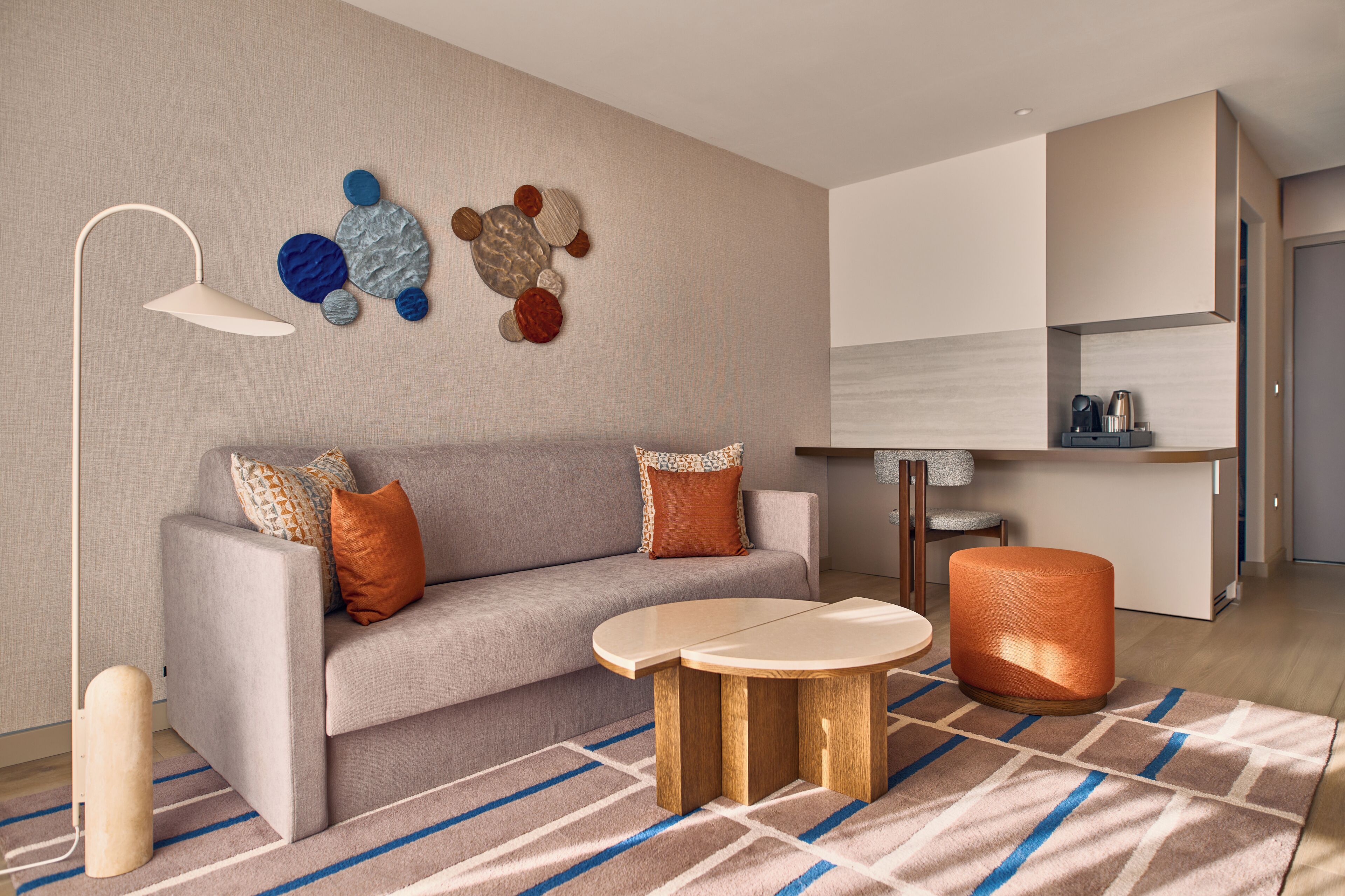 Un salon moderne comprenant un canapé, une table basse, un pouf et une œuvre d’art murale.