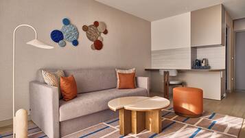 A modern living room with a sofa, coffee table, ottoman, and a wall art piece.