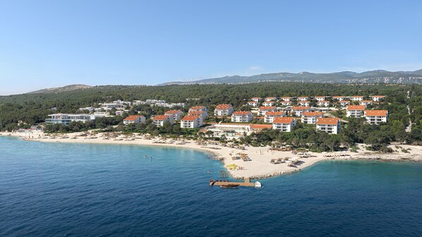 Ein Küstenresort mit Strandvillen, einem Sandstrand und einem Steg.
