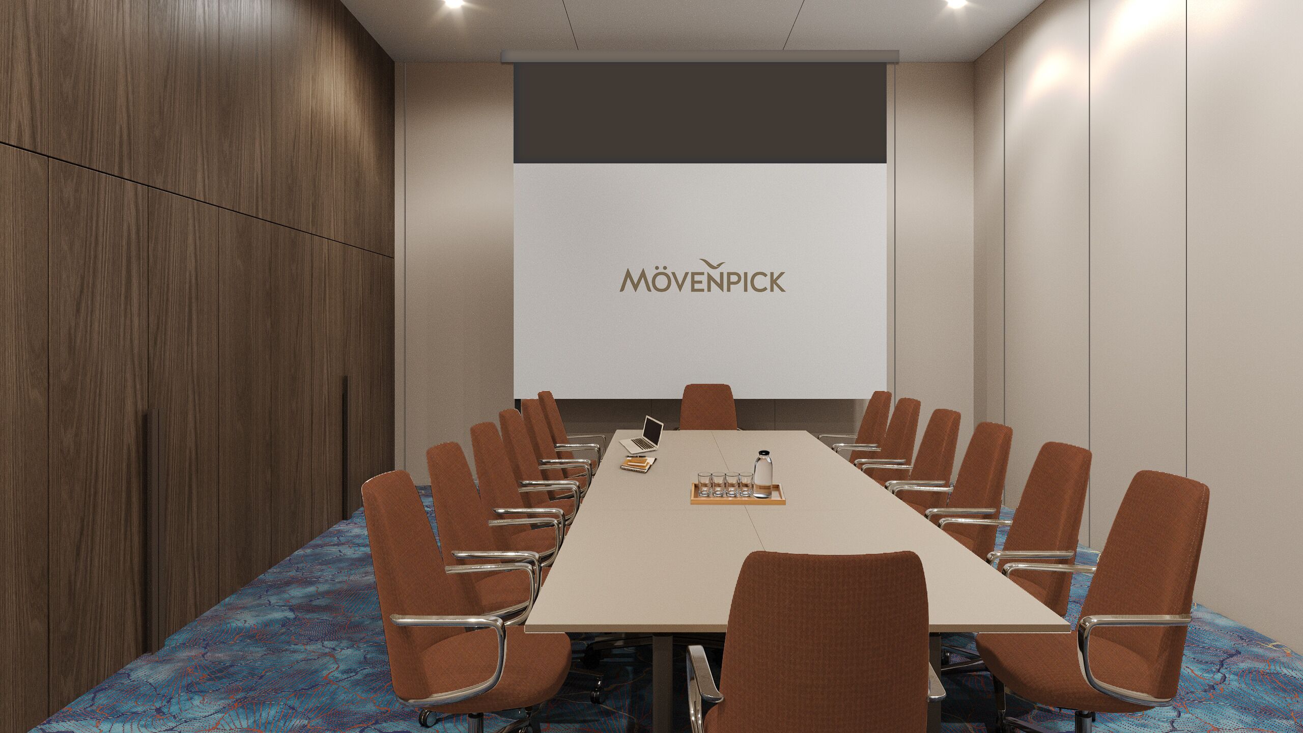 Ein Konferenzraum mit einem langen Tisch, braunen Stühlen, einem Laptop und einer Projektionsleinwand mit dem Schriftzug 'MÖVENPICK'.