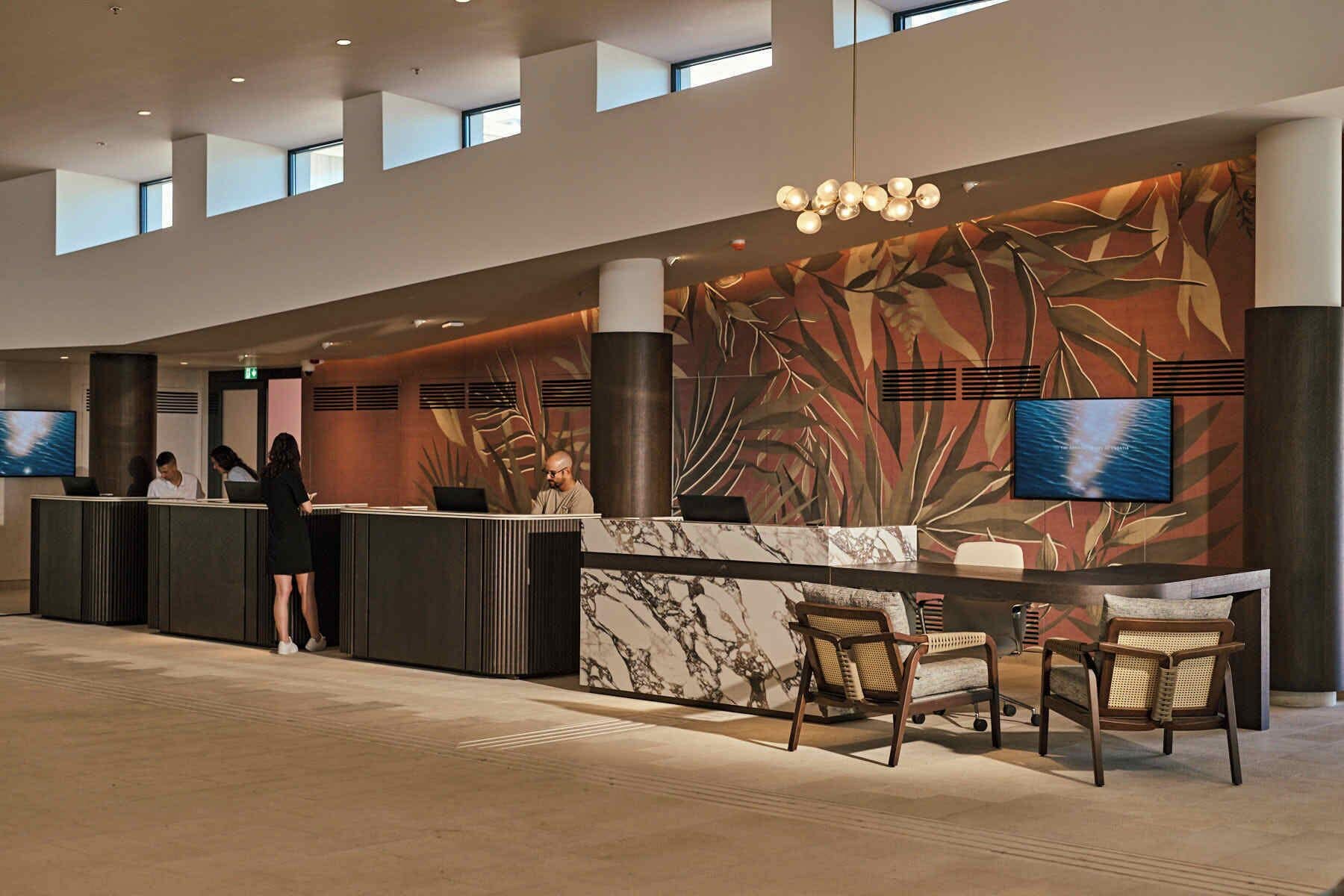 A modern reception area with a marble counter, seating, and large windows.