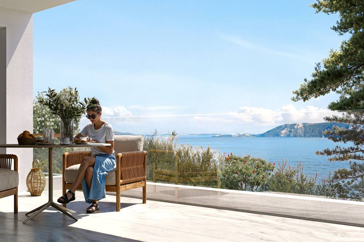 Un espacio exterior moderno con zona de estar y vistas al mar, que incluye mobiliario de mimbre y una mesa con un jarrón de flores.