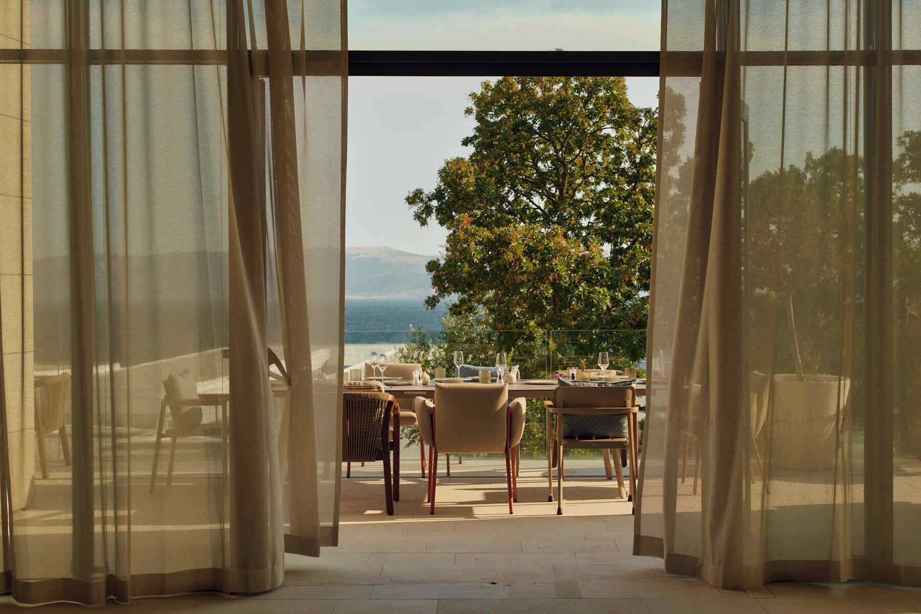 An open patio with a table set for dining, overlooking a tree and a distant landscape.