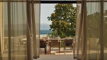 An open patio with a table set for dining, overlooking a tree and a distant landscape.
