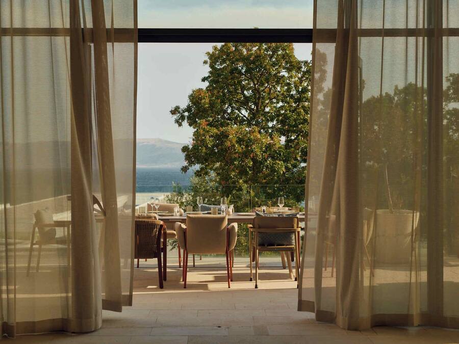An open patio with a table set for dining, overlooking a tree and a distant landscape.