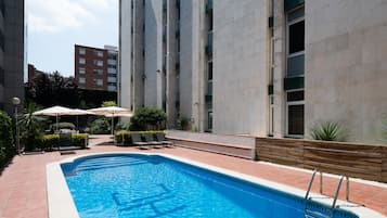 Una piscina al aire libre, sillones reclinables de piscina