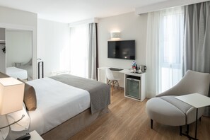 Una habitación de hotel con cama, escritorio, silla, televisor y una pequeña kitchenette.