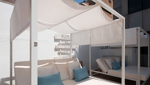 Un espace extérieur aménagé avec des sièges blancs, des coussins, un auvent et un panneau affichant des phrases motivantes.