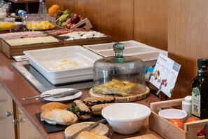 Un bufé con diversos alimentos, entre ellos pan, queso y frutas.
