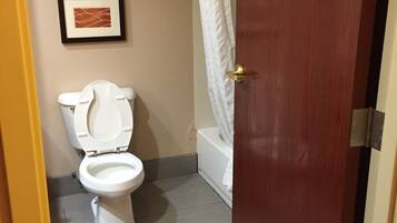 A bathroom with a toilet, a bathtub, and a shower curtain. There are two framed pictures on the wall.