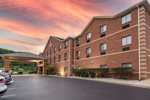 A brick hotel with a covered entrance and a parking lot.