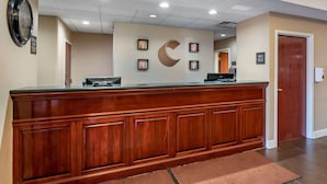 A reception area with a wooden reception desk, a clock, framed artwork, and a sign indicating a check-in desk. - Comfort Inn & Suites Lawrenceburg (Lawrenceburg)